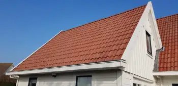 Sneek een woning met rode dakpannen voorzien van zwarte dakcoating