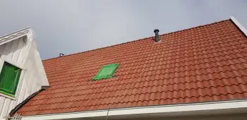 Sneek een woning met rode dakpannen voorzien van zwarte dakcoating